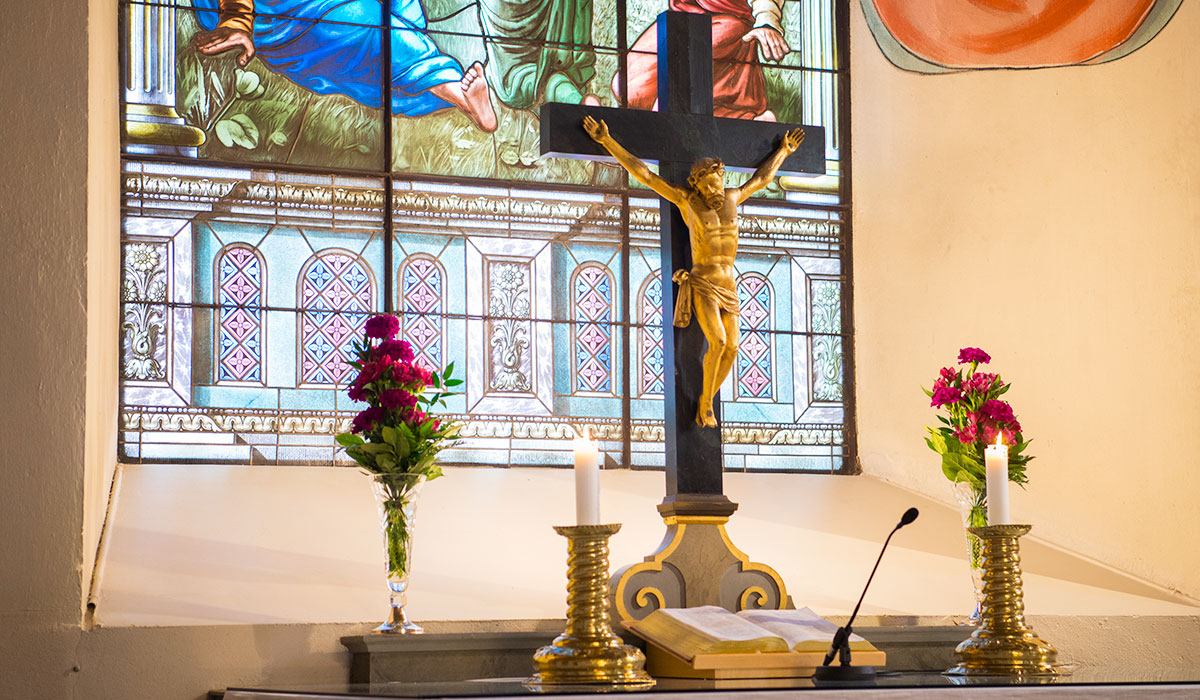 Pyhän Ristin kirkon alttari, Jeesus ristillä, kynttilät ja kukkia.