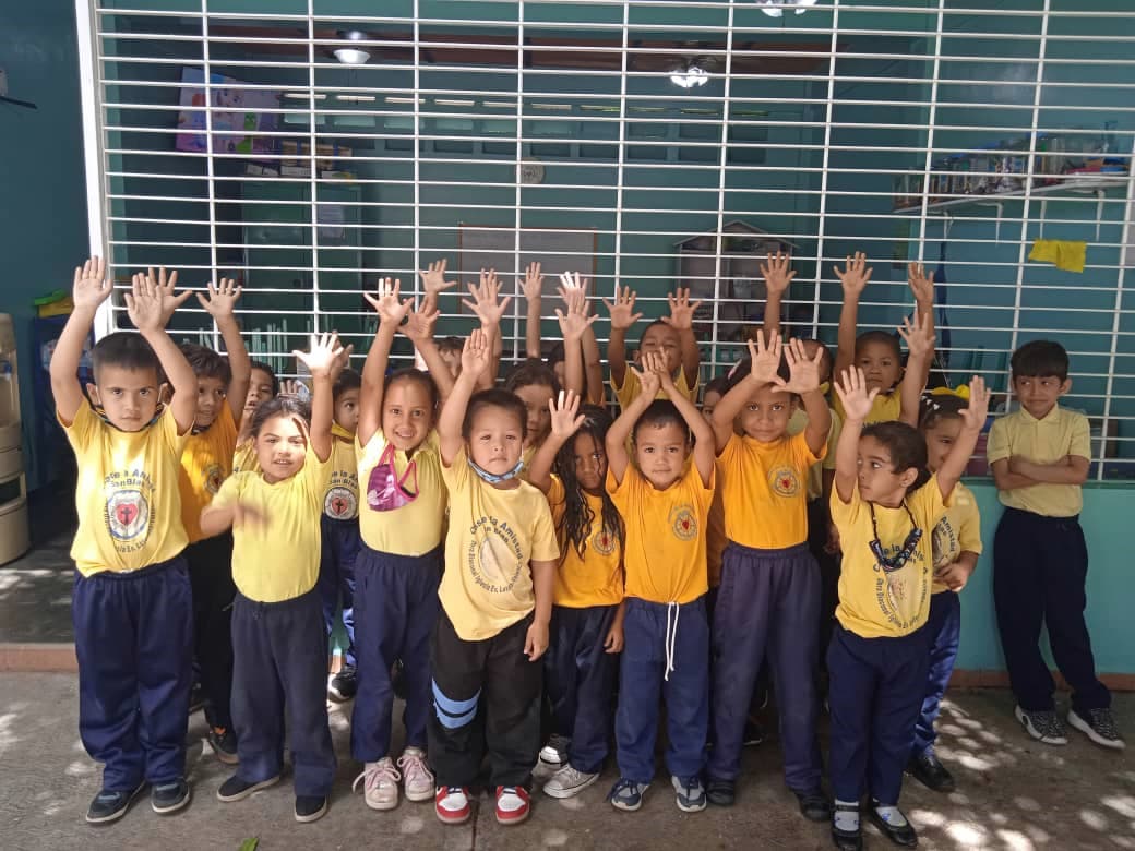 Venezuelalaisia esikoululaisia keltaisissa paidoissa kädet nostettuna pään yläpuolelle.