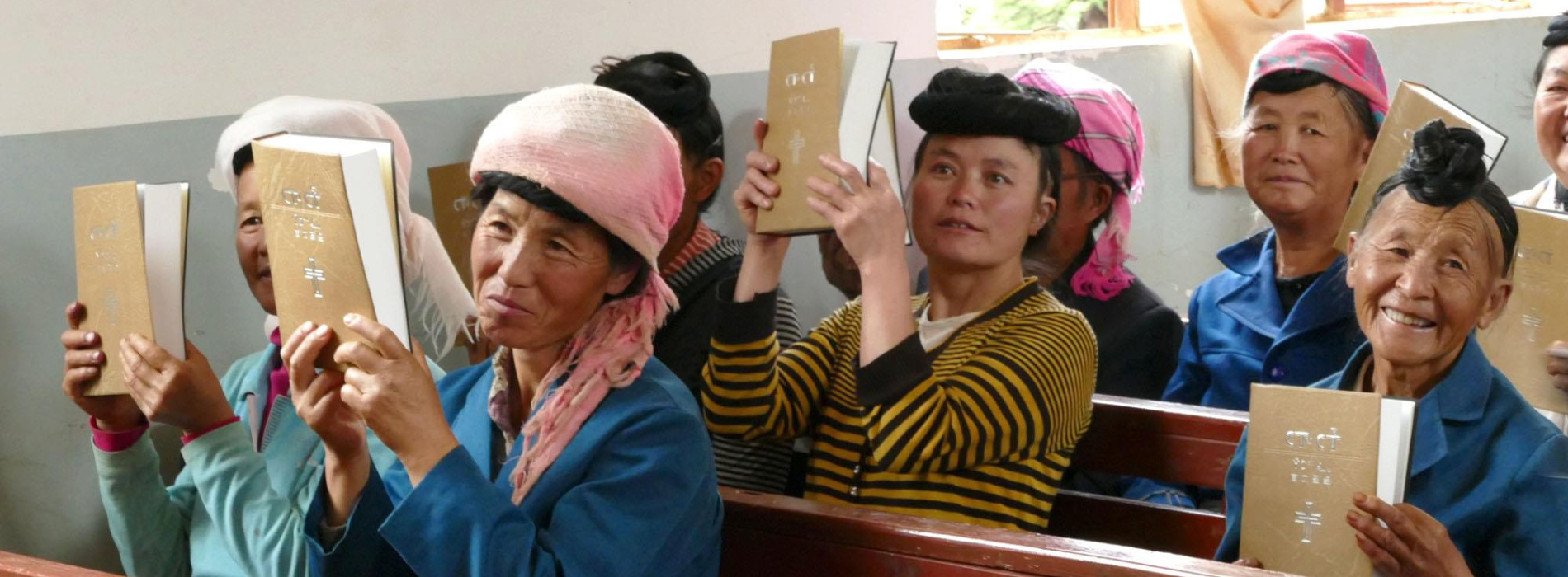 Kiinalaisia kirkon penkeillä käsissään kiinalaisia Raamattuja