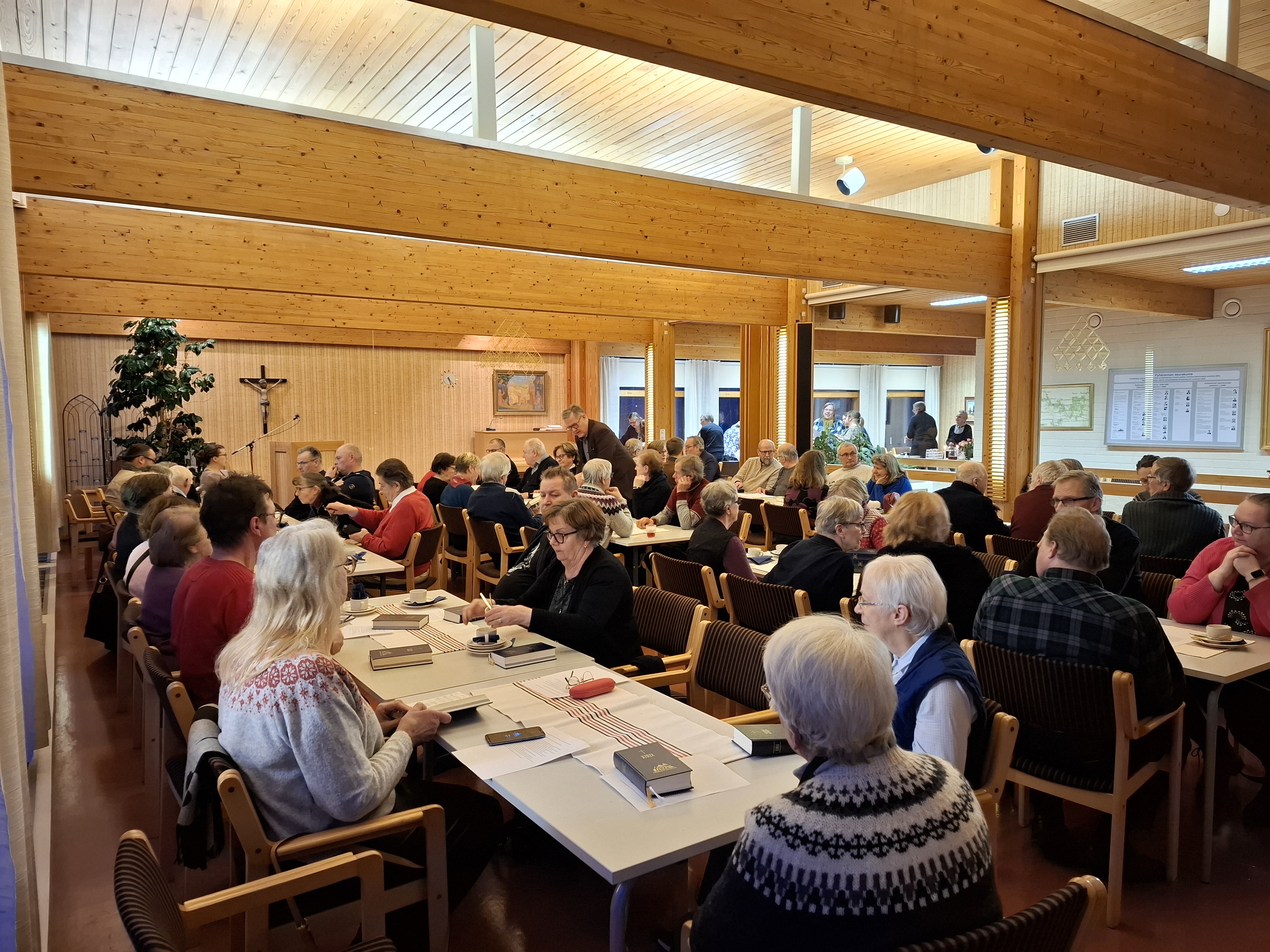 Ihmisiä sisätiloissa pöytien ääressä