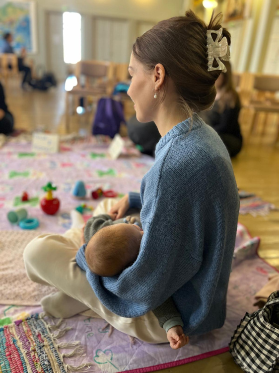 äiti istuu lattialla vauva sylissään