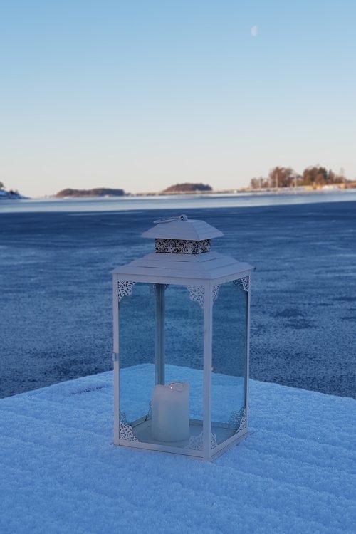 Lyhty ja kynttilä lumisella laiturilla
