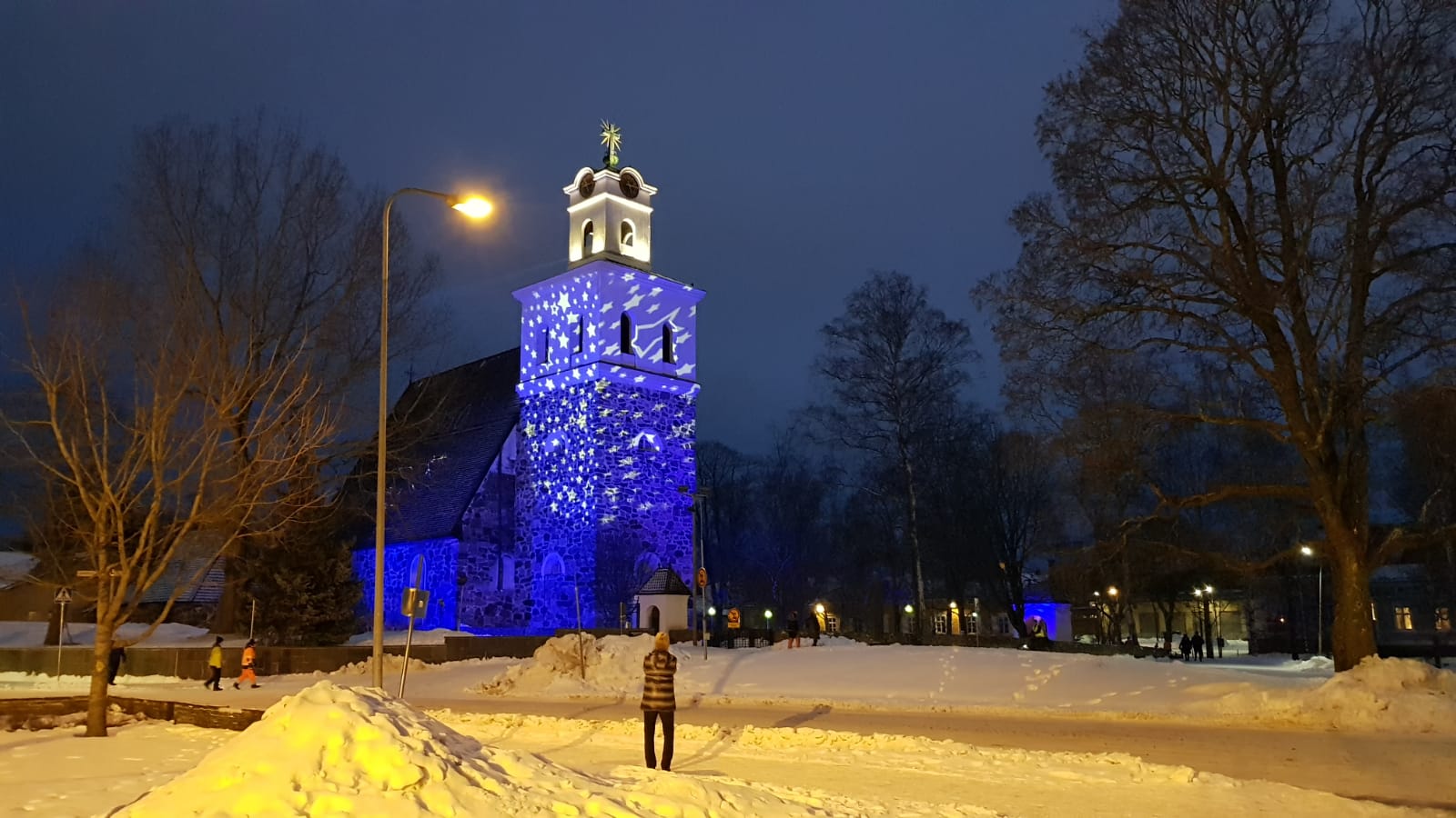 Pyhän Ristin kirkko valastuna sinisellä valoilla ja tähdillä. Luminen ulkomaisema.