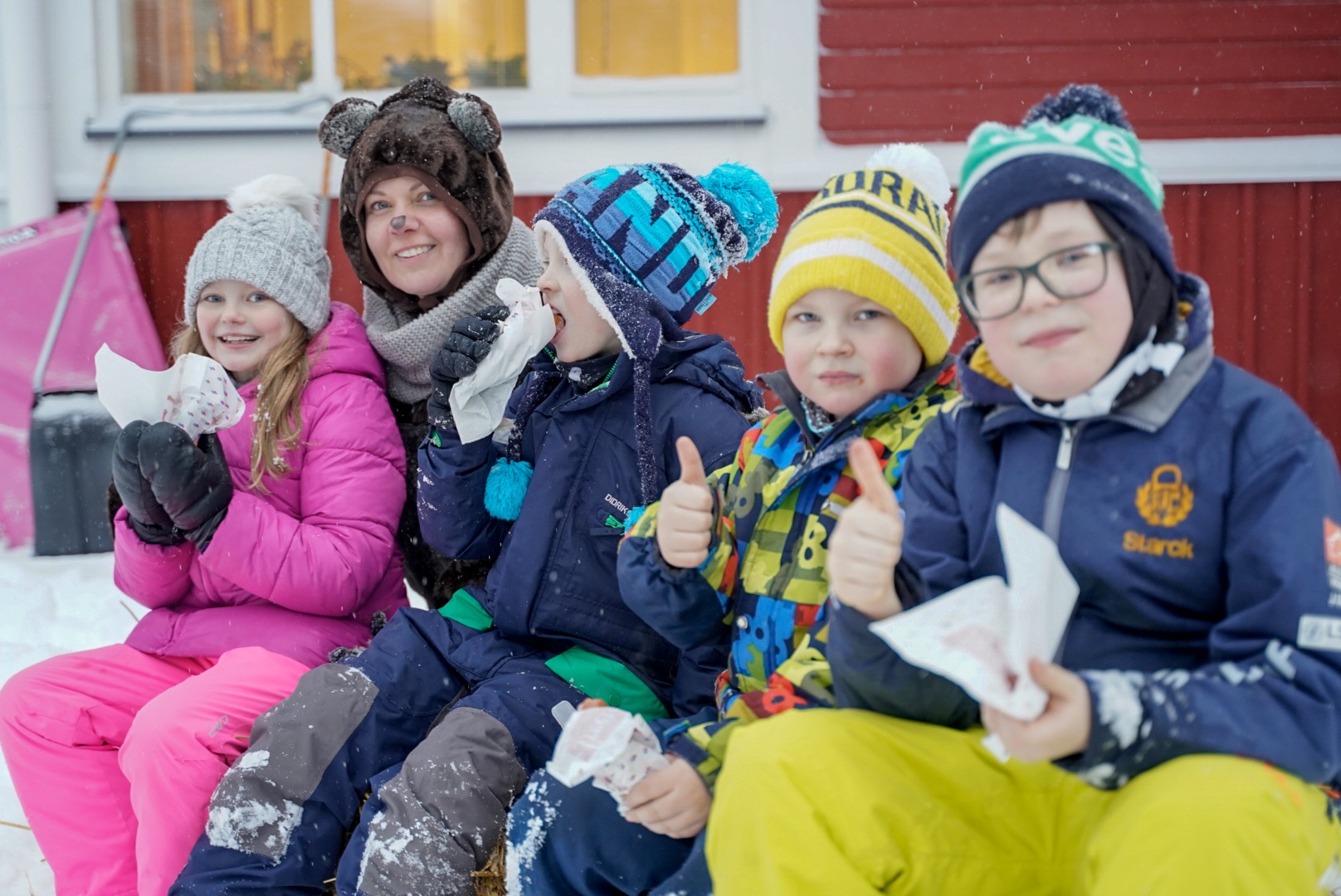 Lapset syövät makkaraa ulkona talvella