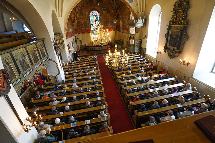 Kirkkosali jossa näkyy paljon ihmisiä istumassa kirkon penkeissä
