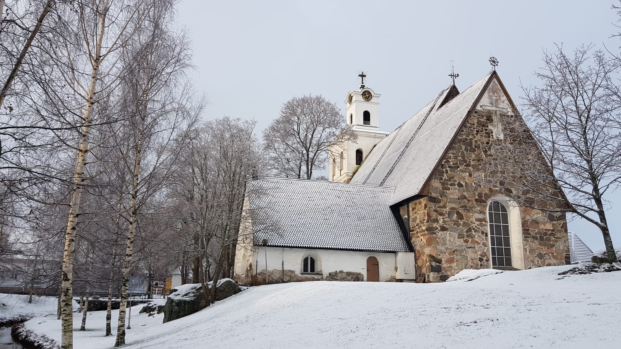 Luminen maisema. Vanha kivikirkko ja puita.