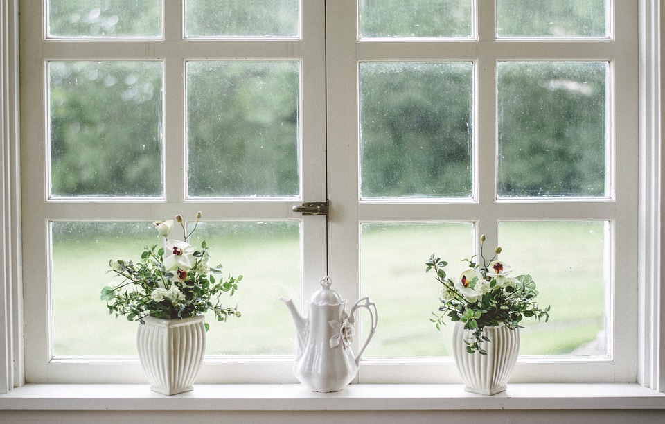 Valkoiset ruutuikkunat. Ikkunalaudalla valkoisia kukkia.