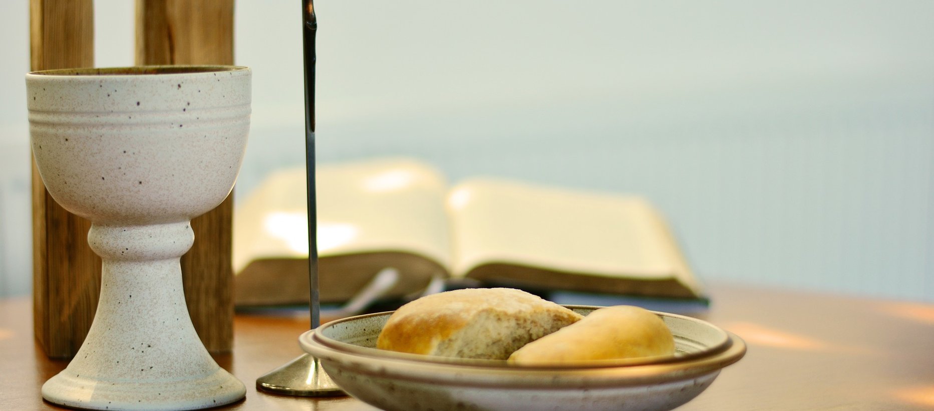 Ehtoollispikari, ehtoollisleipä ja raamattu lähikuvassa pöydällä