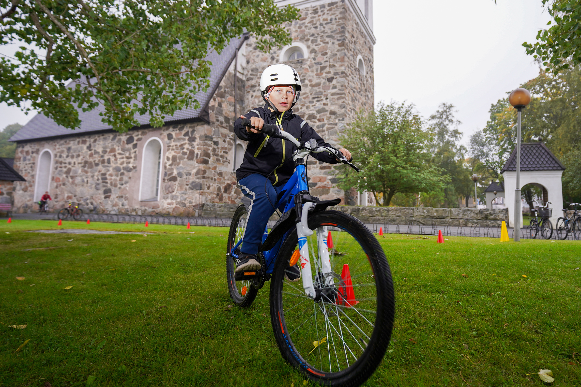 Poika pyörän kanssa kirkon edessä.