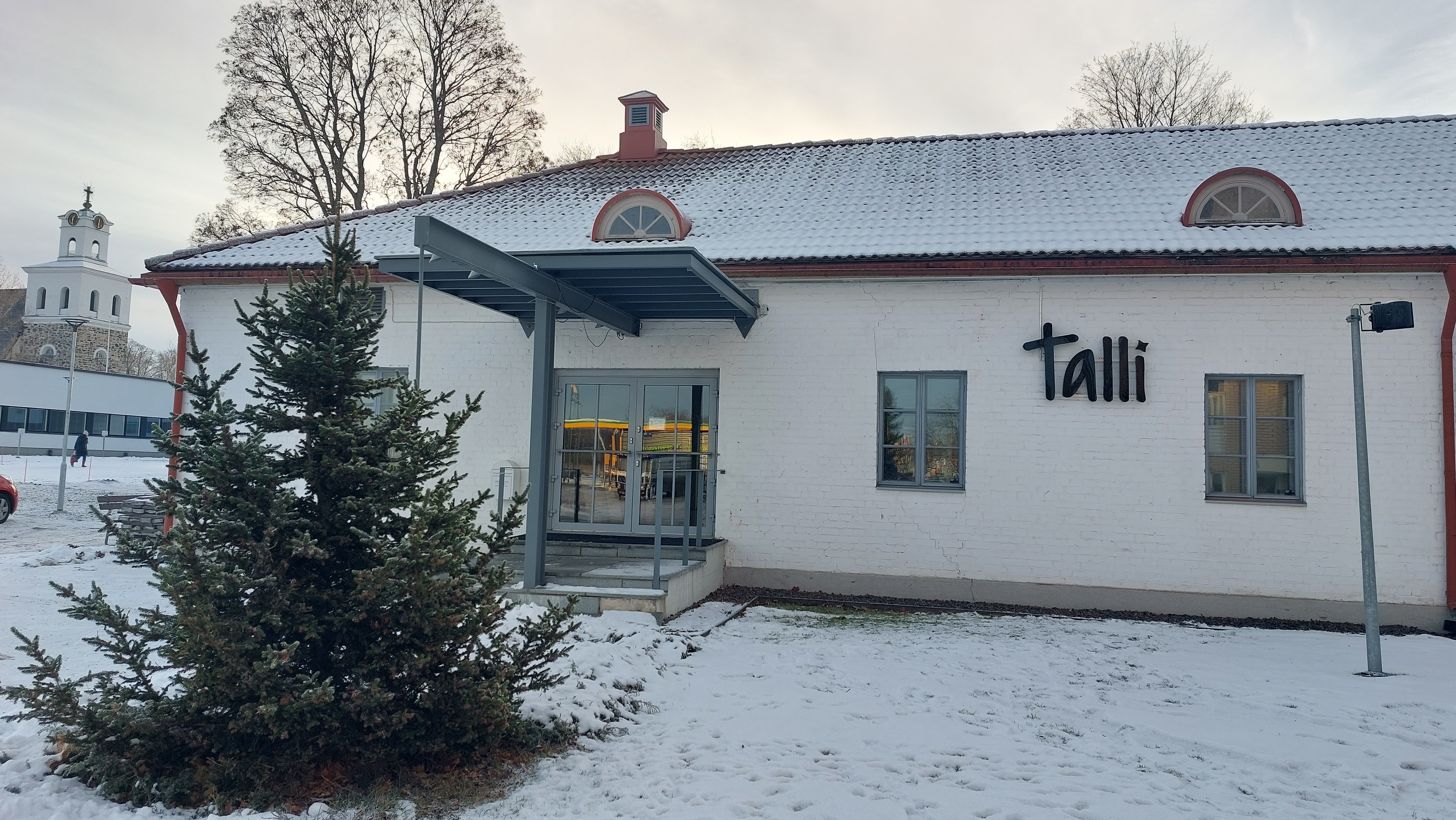 Talvinen kuva seurakunnan uudesta Talli -nimisestä kasvatuksen toimitilasta. Rakennuksen seinällä teksti Ta...